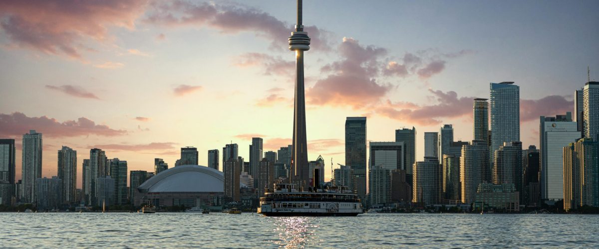 Stunning Toronto skyline at sunset, highlighting the CN Tower and waterfront from Lake Ontario.